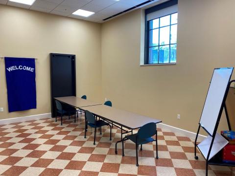 picture of the children's program room, showing one table with chairs surrounding it, and a mobile dry erase board