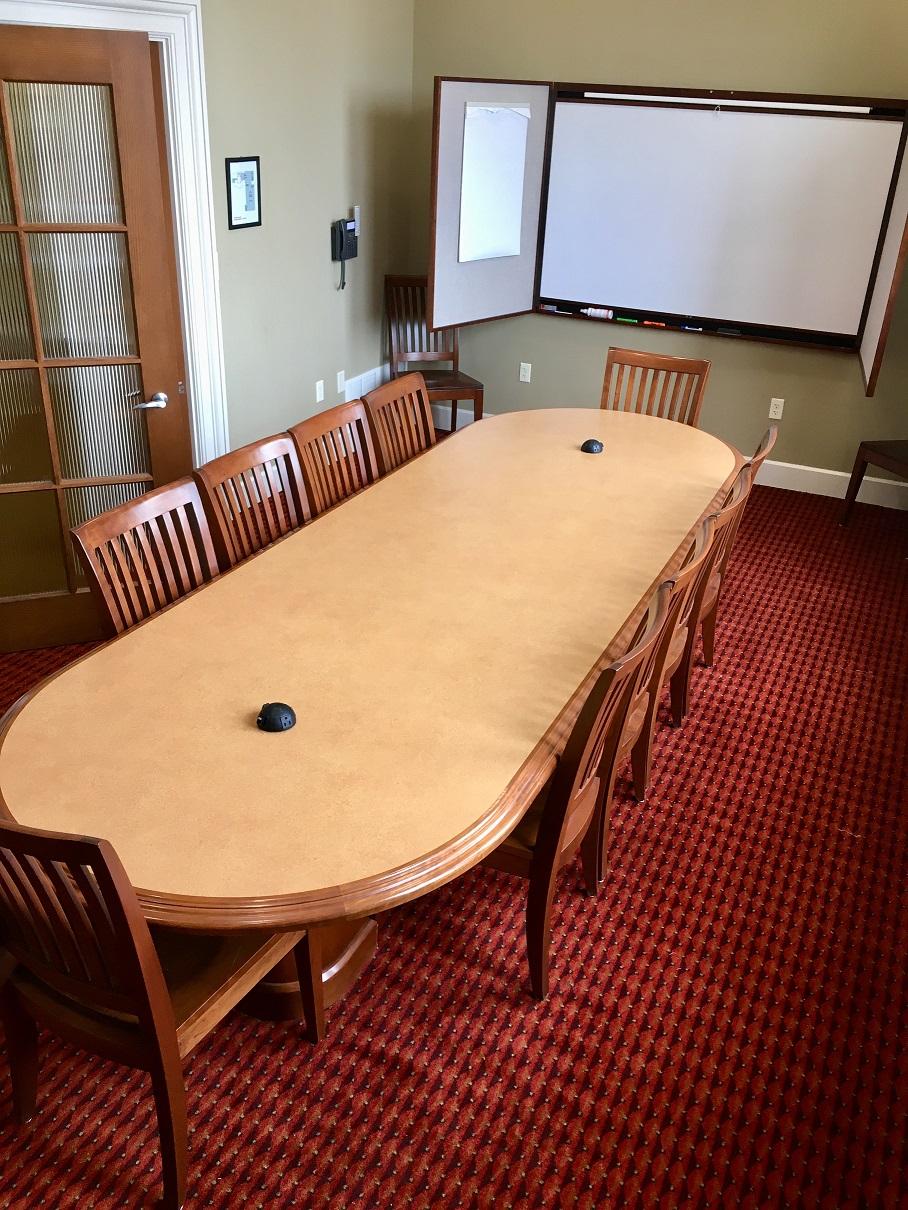 picture of the large meeting room showing a table surrounded by chairs and a dry erase board